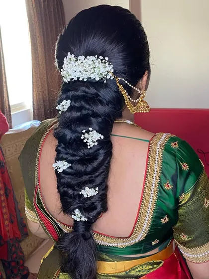 A messy braid for an engagement, decorated with baby's breath. This romantic and textured hairstyle is a beautiful choice for a modern bride.