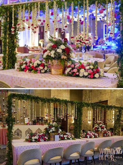 A two-part image showing the elegant buffet table decor. A canopy of greenery and hanging floral tassels frames the table, which is adorned with beautiful arrangements of red and white flowers.