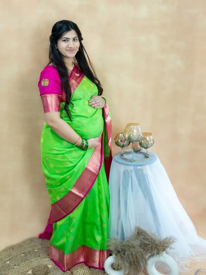 A beautiful studio portrait celebrating tradition. This mom-to-be looks lovely in a bright green and pink silk saree.