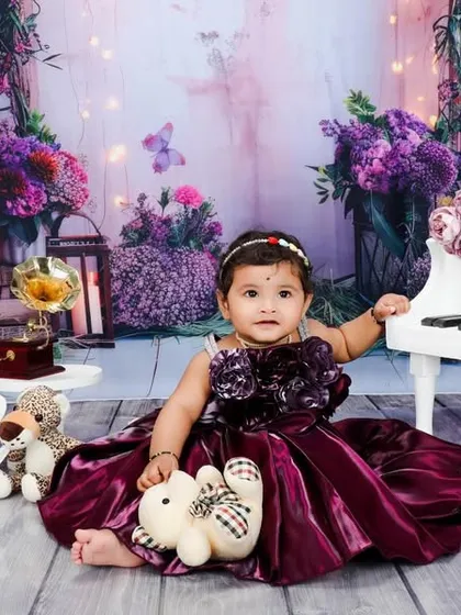 A little musician in the making. This first birthday setup features a miniature white piano adorned with flowers against a royal purple backdrop, creating a whimsical and elegant portrait.