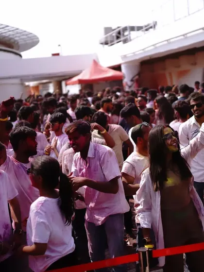 A wide shot of the happy, color-covered crowd at a Holi party. This is what a successful festival looks like.