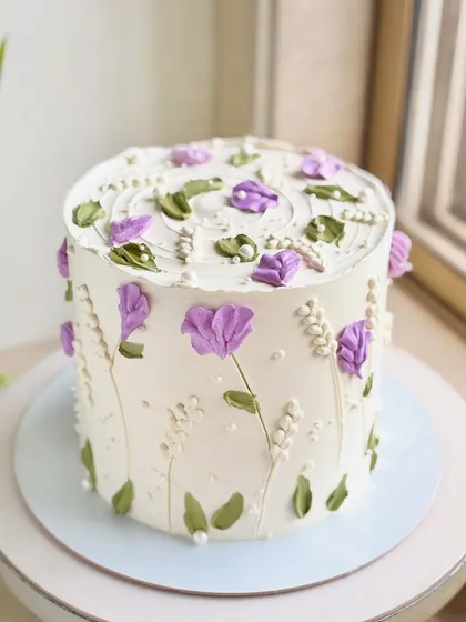 A full view of the purple floral cake, showing how the design wraps around the sides and covers the top in a beautiful, garden-like pattern.
