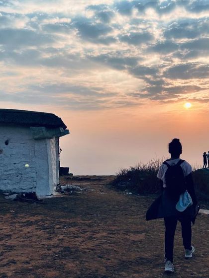 A trekker walks towards a small shrine at the top of Kaiwara Betta as the sun rises.