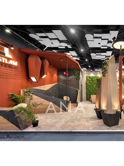 The reception and branding area for the Trustlam '23 stall featured geometric, multi-layered forms and bold colors. Abstract light fixtures on the wall echo the 'flame' concept of the main sculptures.