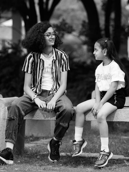 A candid black and white shot of two sisters sharing a moment. The monochrome edit adds a nostalgic and timeless feel to their interaction.