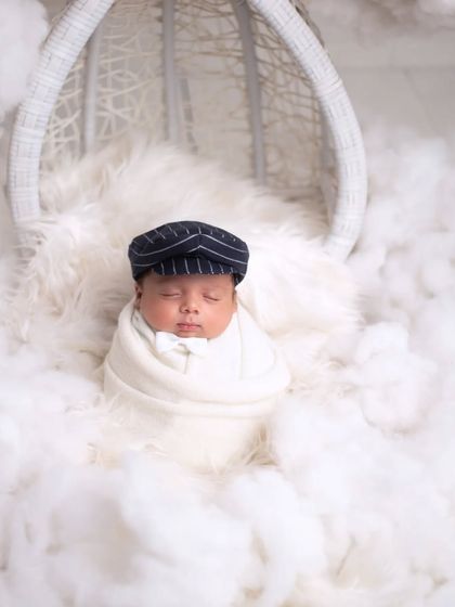 Dreaming on a cloud. This creative setup uses soft, fluffy material to create the illusion of clouds, with the baby sleeping peacefully in a hanging chair.