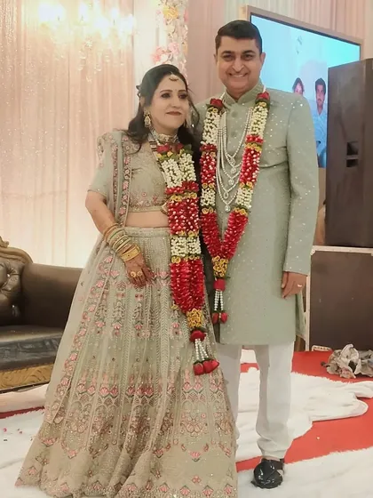 A lovely couple posing in their reception outfits. Her light green lehenga with subtle pink embroidery matches his elegant light green sherwani.