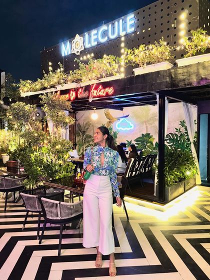 Posing outside the bar, this outfit shows how a good floral top can be dressed up for an evening look. The white pants keep it feeling fresh and modern.