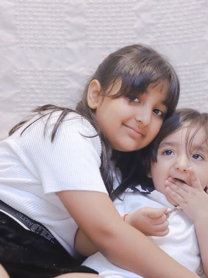 A candid moment of two siblings cuddling on a bed. Our lifestyle sessions capture your family's love in a natural, comfortable setting.