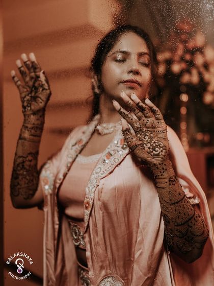 An artistic and moody shot of the bride with her Mehendi-adorned hands, captured through a window.