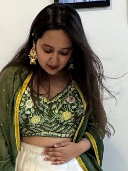 A close-up on the beautifully embroidered green blouse, which features delicate floral patterns that complement the painted skirt.