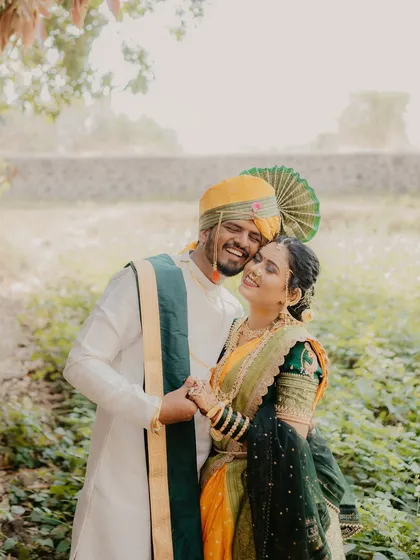 A sweet and joyful embrace. The couple's radiant smiles and the natural, rustic background create a warm and authentic portrait of their love.