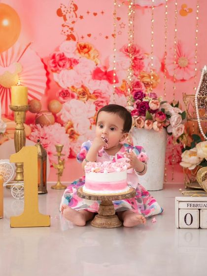 A sweet moment with the birthday cake. The soft, warm lighting and pink floral background create a beautiful and celebratory atmosphere.