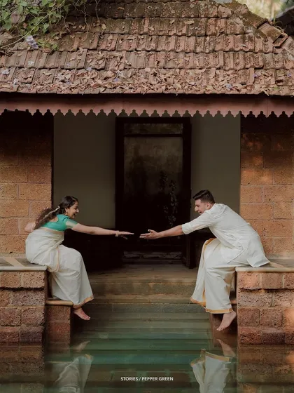 A creative and symbolic shot of the couple reaching for each other across a temple pond.