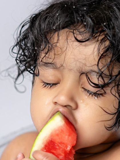 A close-up of a baby enjoying a slice of watermelon in the tub. A moment of pure, sensory delight.