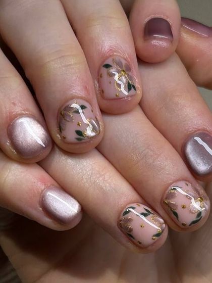 A delicate and sophisticated nail art design. This set features a soft pink cat-eye base with accent nails adorned with hand-painted floral details and gold flakes.