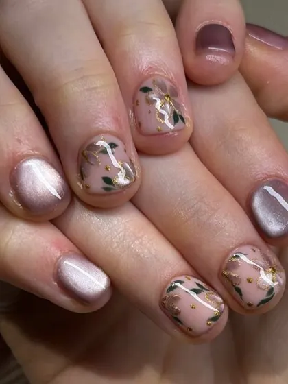 A delicate and sophisticated nail art design. This set features a soft pink cat-eye base with accent nails adorned with hand-painted floral details and gold flakes.