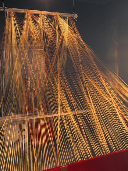 An art installation of golden threads representing the warp of a loom. This conceptual shot for Kanakavalli visualizes the very beginning of a Kanjivaram saree's life.