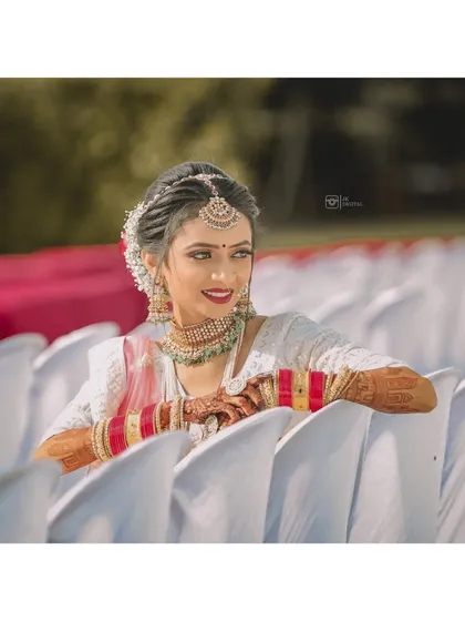 A beautiful portrait of a bride, relaxed and smiling, on her wedding day. The soft background helps her traditional white and red bangles stand out.