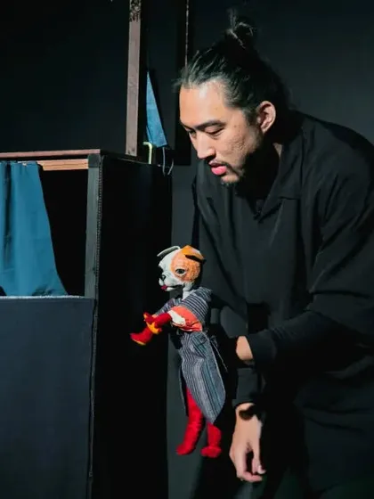 The puppeteer demonstrates the expressive movement of the dog glove puppet. His focus and skill bring the character to life.