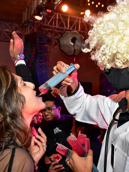 The party doesn't stop! Another guest enjoying a fun syringe shot from Dr. Gulati, surrounded by the energetic atmosphere of the event.