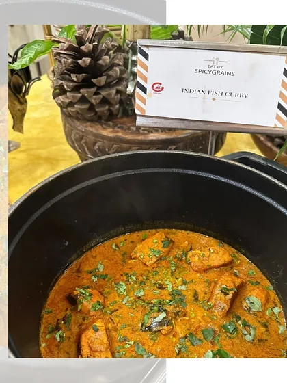 A delicious and comforting Indian Fish Curry, garnished with fresh cilantro, served hot in a modern cooking pot.
