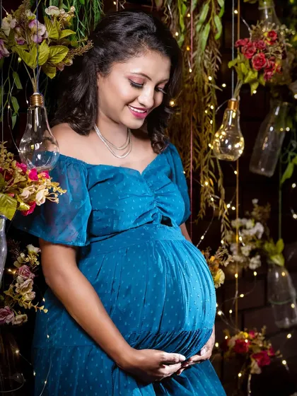 A beautiful portrait in a rustic, boho-inspired setting. The warm fairy lights, hanging plants, and blue dress create a cozy and magical atmosphere.