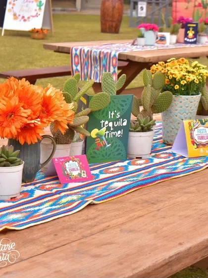 A close-up of the picnic table decor, showing the mix of live cacti in pots and vibrant floral arrangements.