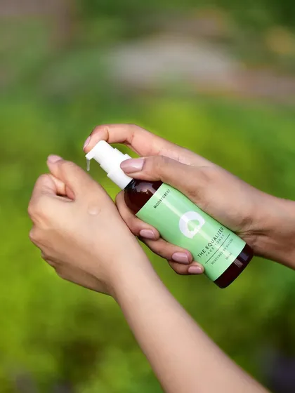 An in-use lifestyle shot of Moon Forest's face toner being applied to the wrist. This demonstrates the product's texture and application in a natural, outdoor setting.