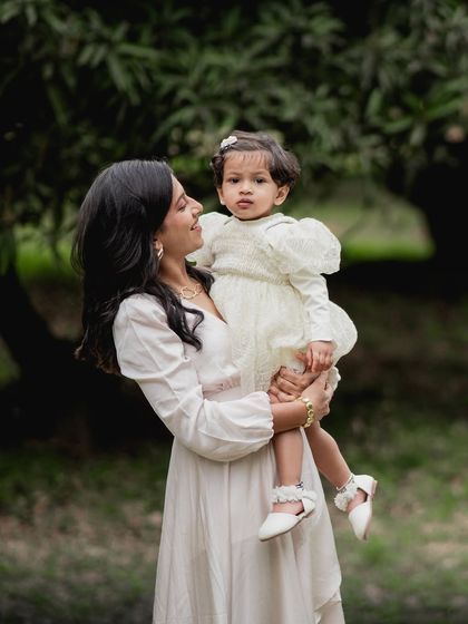A mother holding her daughter during an outdoor photoshoot.