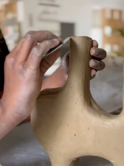 A student smoothing the edges of a complex, multi-spout vase. Hand-building is all about patience and precision.