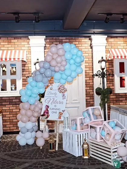 A charming party setup with a brick wall backdrop, pastel balloon arch, and themed props, showcasing a "We Can Bearly Wait" baby shower or birthday theme.