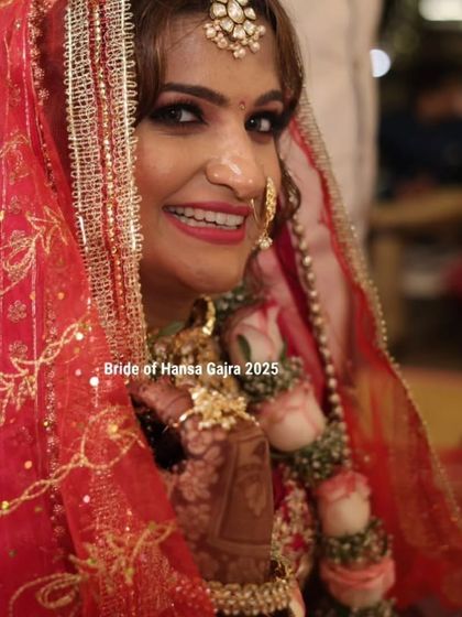 A close-up of a smiling bride on her wedding day. Her red lehenga, floral jewelry, and intricate mehendi create a look of timeless beauty and joy.