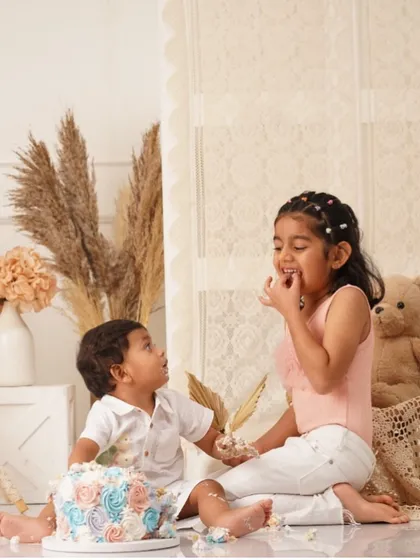 The sweetest moment of sharing! The older sister helps her baby brother with his smash cake.
