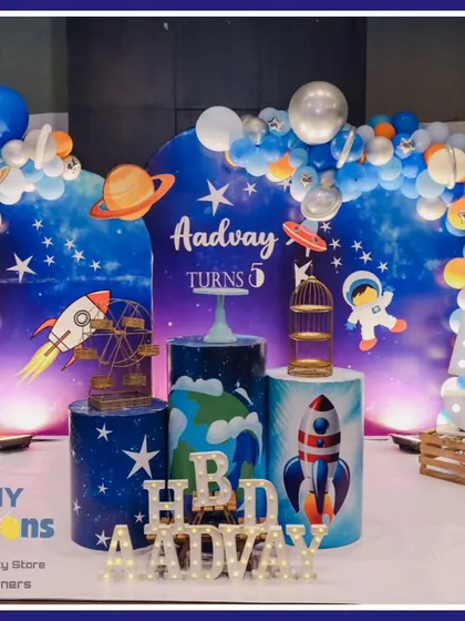 An out-of-this-world space theme for a 5th birthday celebration. This setup features a galaxy-inspired backdrop, a balloon arch with planet details, rocket ship cutouts, and themed dessert stands, ready for a cosmic adventure.