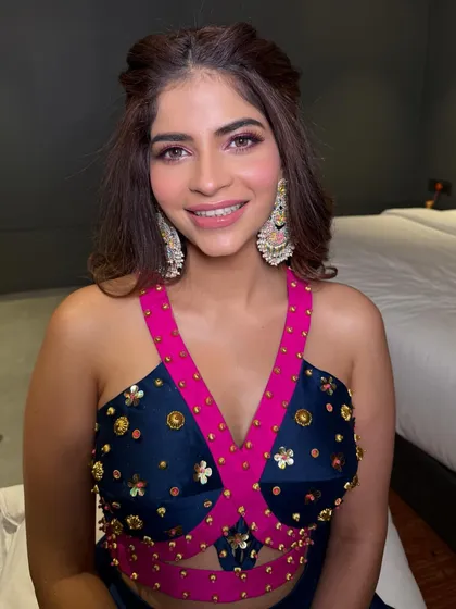The client looks happy and ready to celebrate in her colorful outfit, with a hairstyle that is both stylish and comfortable for a day of festivities.