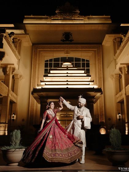A romantic portrait of the couple dancing in front of the illuminated hotel facade at night.