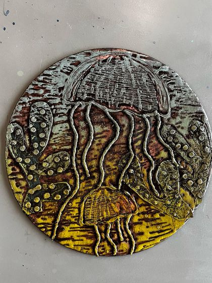 This circular collagraph print features delicate jellyfish brought to life with varied textures and a beautiful color palette. It's a wonderful example of the imaginative scenes our students create.