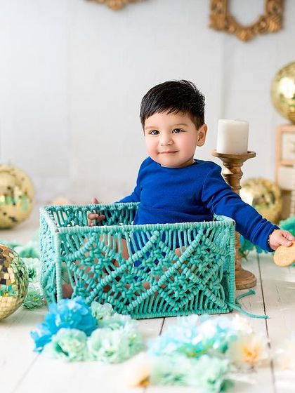 A handsome little boy posing in a stylish teal basket. Sitter sessions are a great way to capture your baby's personality as they start to explore the world.