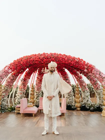 The groom stands proudly before the magnificent floral mandap, ready and waiting for his bride. A powerful portrait full of anticipation.
