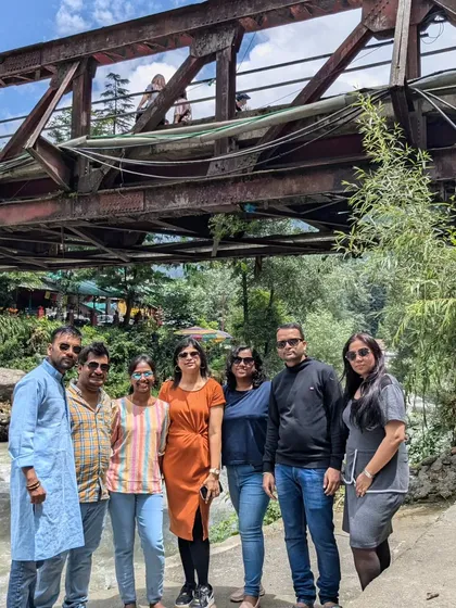 A group photo near a bridge in Old Manali. The Beas River and pine-covered hills provide a classic Himachali backdrop.