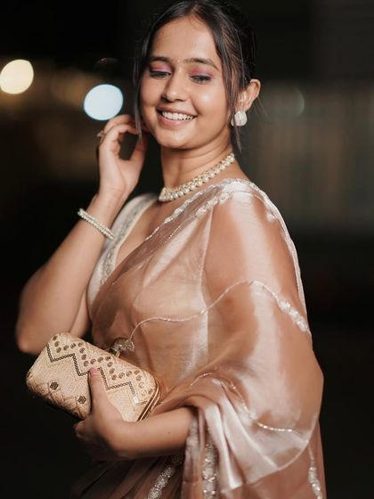 Elegance and grace for an evening affair. This beautiful beige organza saree with delicate handwork is perfect for a classy, understated look. Pair it with pearls to complete the ensemble.