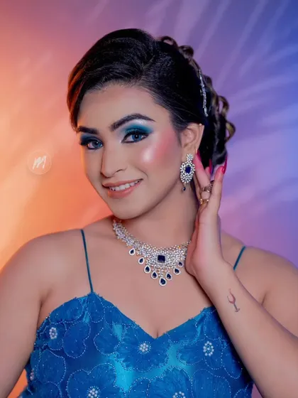 A smiling portrait showing the bold blue eye makeup.