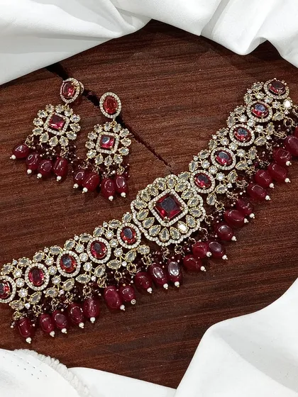 A rich maroon stone choker set with antique gold finish, perfect for traditional ceremonies.