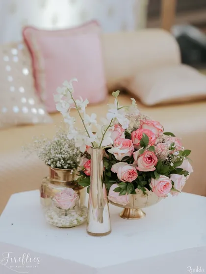 A delicate floral arrangement of pink roses and baby's breath in metallic vases, adding a touch of soft romance to the lounge seating.
