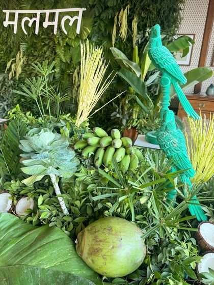 A close-up of the tropical installation for Shop Mul Mul, showing green coconuts, bananas, and vibrant green parrot props against the brand's backdrop.
