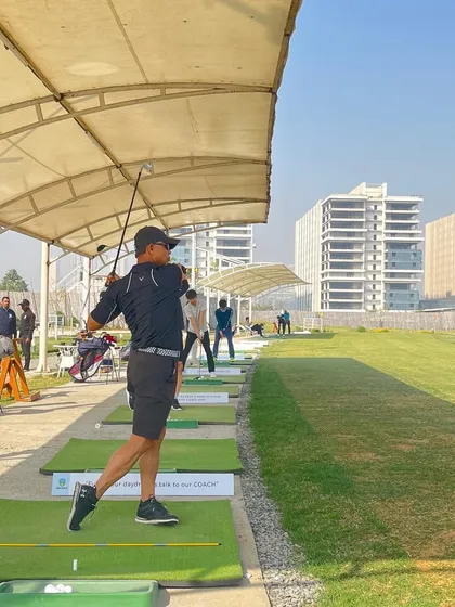 A view down the line of our covered hitting bays, bustling with golfers enjoying a sunny day on the range.