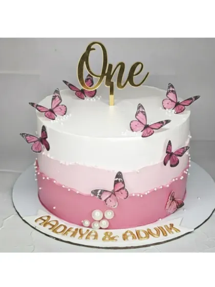 A dreamy pink ombre butterfly cake for twins turning one. This truffle cake is simple yet elegant, with delicate butterflies and a golden "One" topper.