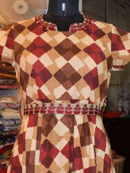 The warm, earthy tones in this diamond-patterned cotton kurti are perfect for the transition from summer to autumn. The delicate embroidery on the waist and neckline adds a touch of festive detail.