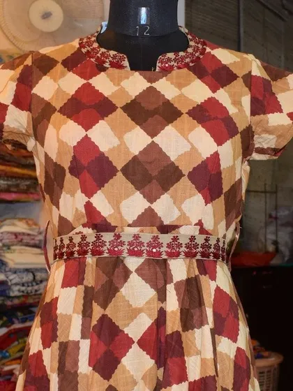 The warm, earthy tones in this diamond-patterned cotton kurti are perfect for the transition from summer to autumn. The delicate embroidery on the waist and neckline adds a touch of festive detail.